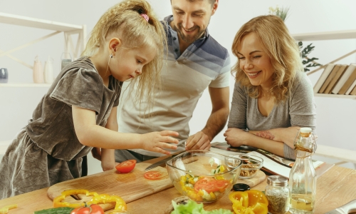 cute-little-girl-her-beautiful-parents-are-cutting-vegetables-kitchen-home